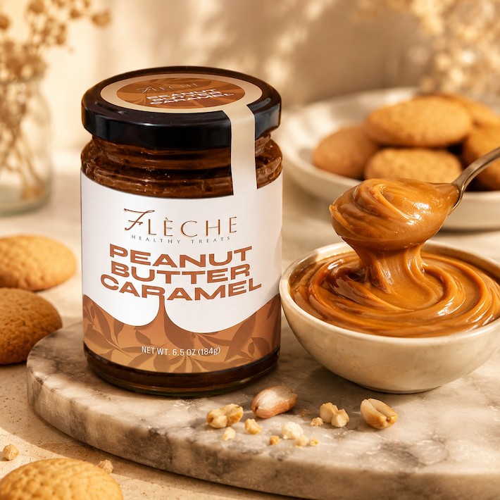 Jar of Fleche Peanut Butter Caramel with a spoonful of the spread on a marble surface.